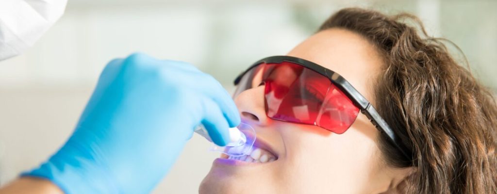 Woman having dental checkup with ultraviolet light
