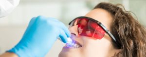Woman having dental checkup with ultraviolet light
